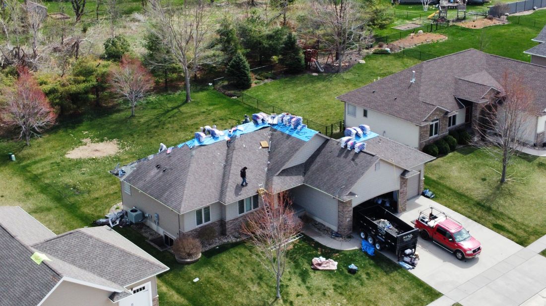 Aerial view of a roof under emergency tarp after storm damage