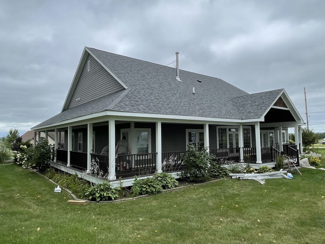 Completed roof on a farmhouse-style home with a wraparound porch