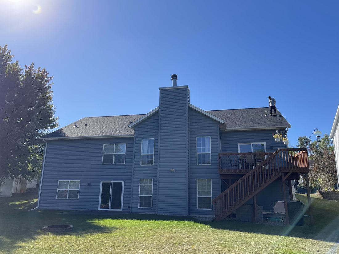Completed roof, rear view of a home with a chimney and deck