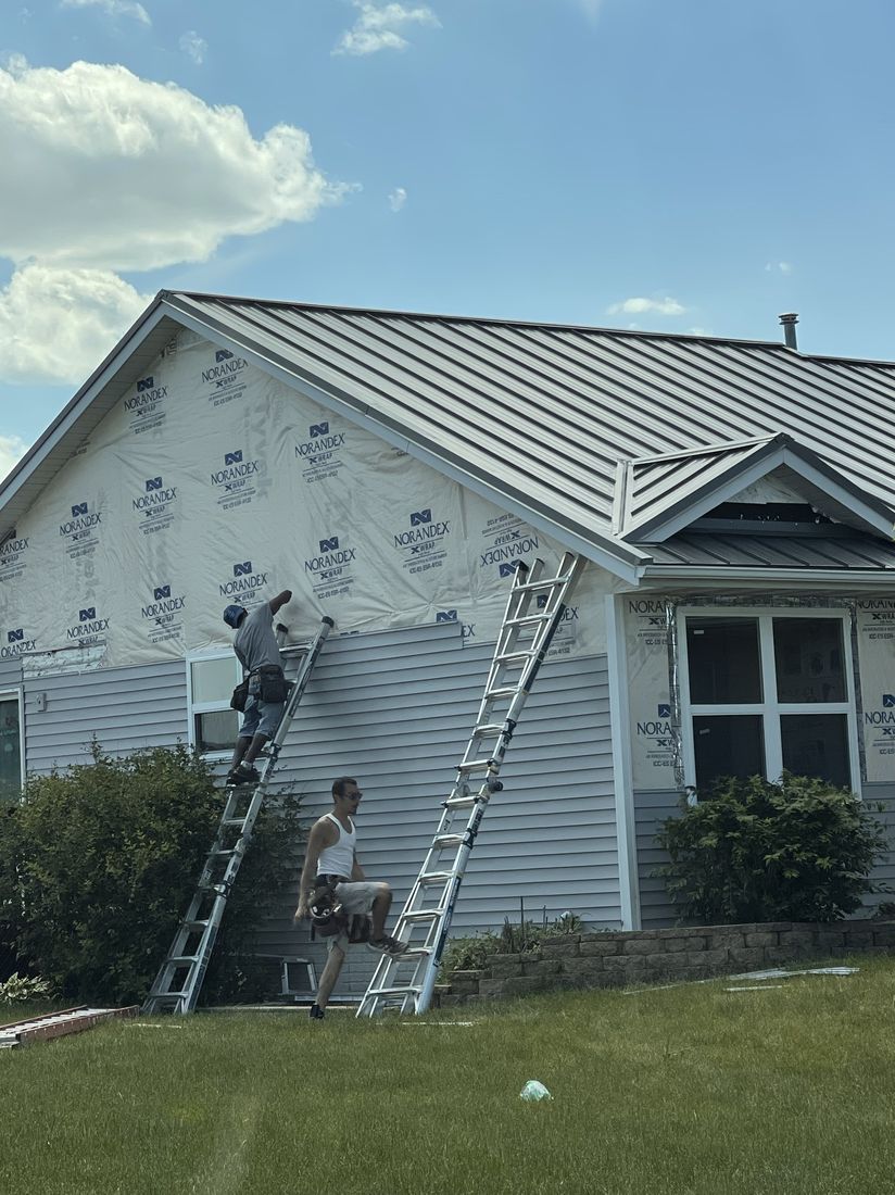 Trego Roofing crew member on a ladder during a roofing job