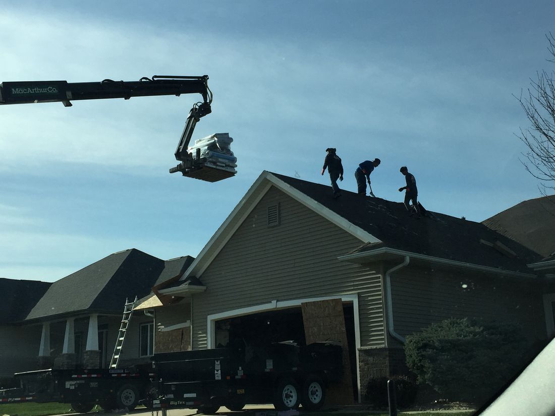 Crane lifting roofing materials onto a roof for a Trego Roofing job