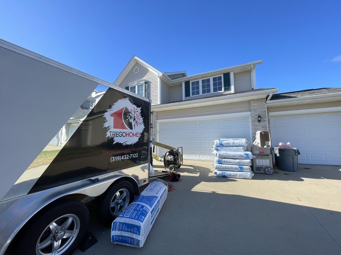 Trego Homes trailer with shingle bundles staged in a driveway